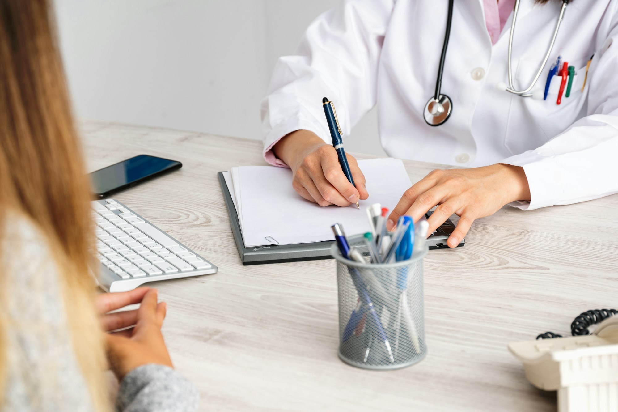 Female doctor in consultation with a patient taking notes