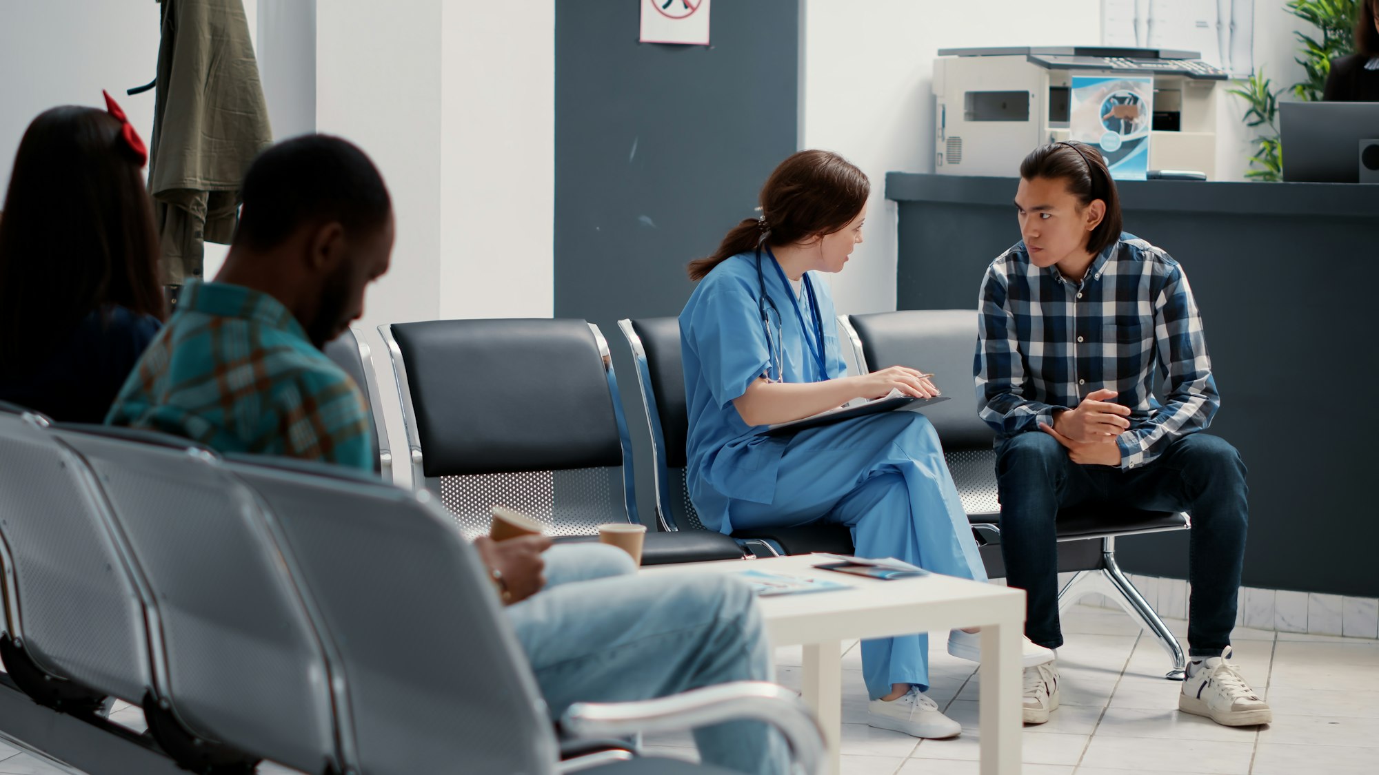 Medical assistant filling in checkup report and talking to asian patient